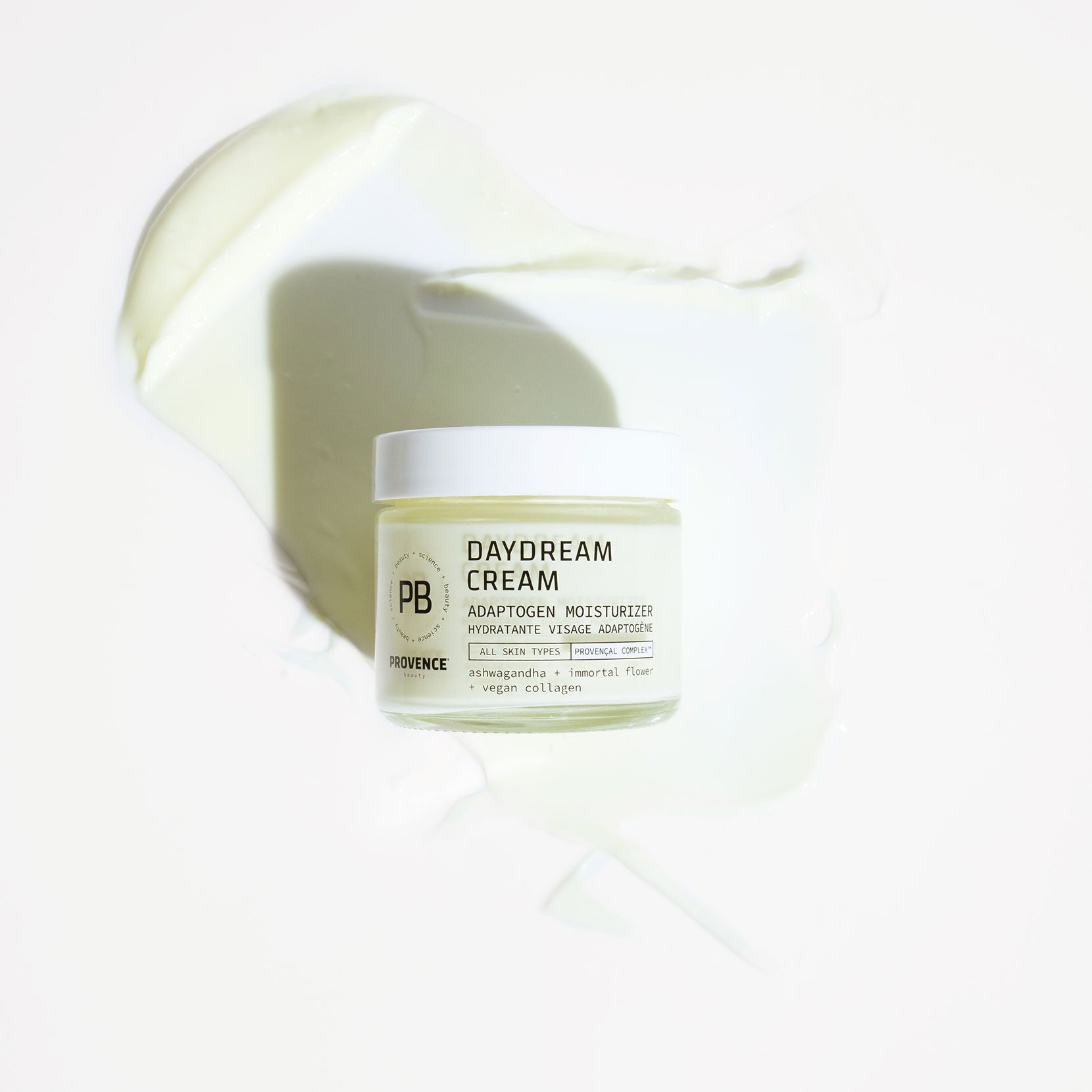 A photo of Daydream Cream Adaptogen Moisturizer glass jar placed on top of the product smeared in the background showing the thick texture.